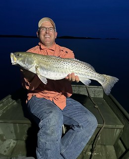 Photo of man in a small boat holding a fish