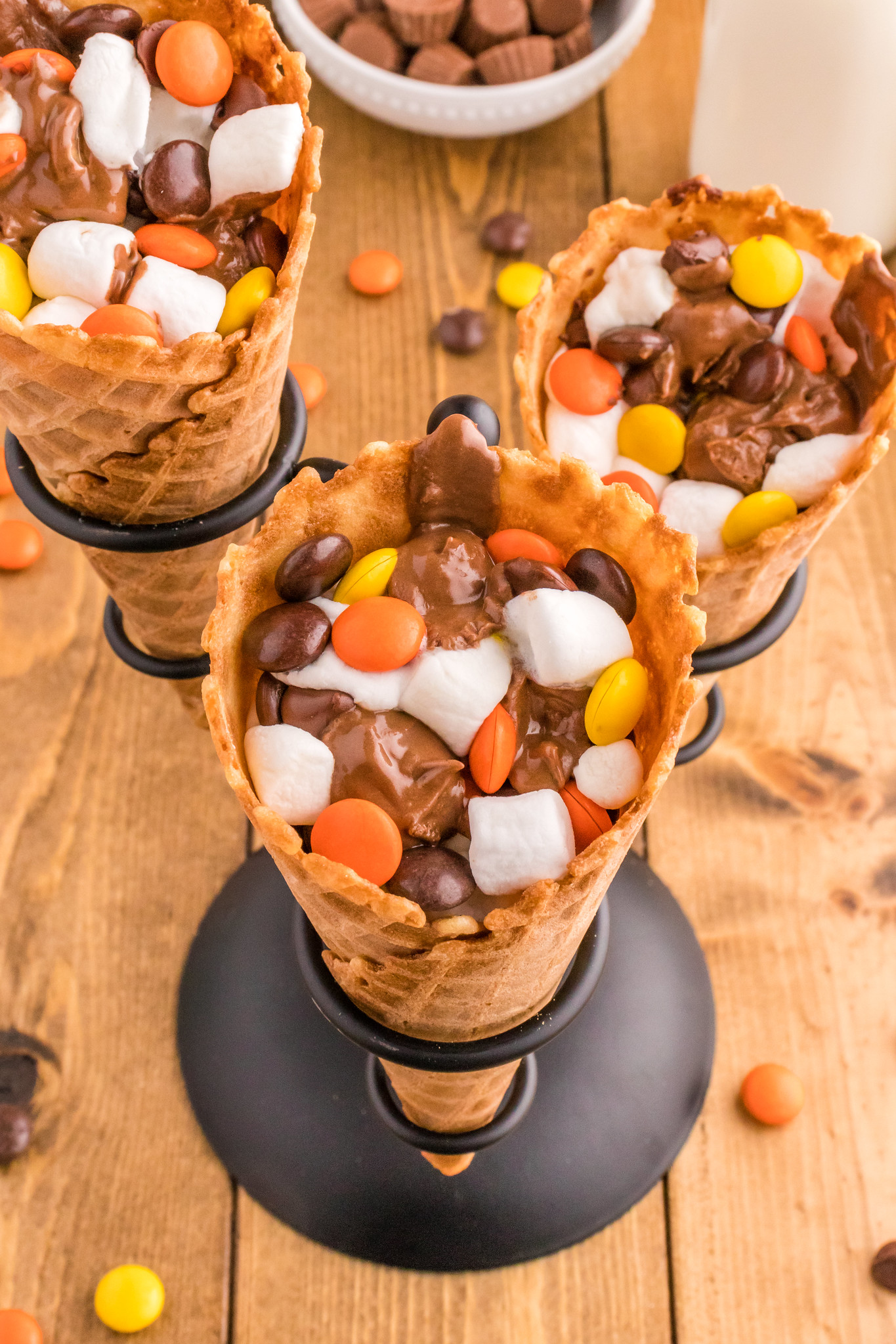 3 reese's campfire cones filled with marshmallows, chocolate, mini peanut butter cups, and reese's pieces