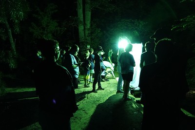 nighttime crowd gathered around a green light and white sheet