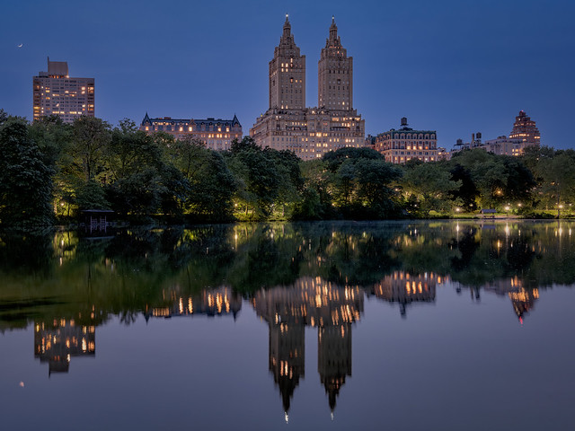 Quarter moon over the West Side of Manhattan at blue hour reflected in the pond in Central Park