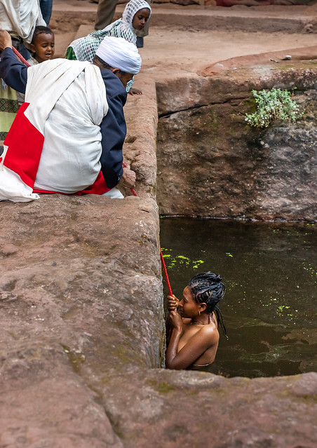 Ethiopian priest helping a woman to take a bath in holy water to fight her infertility, Amhara Region, Lalibela, Ethiopia