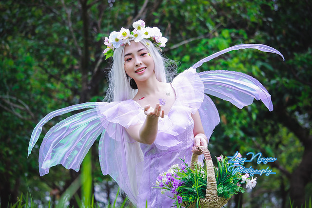 A charming, beautiful girl is transforming and posing in the character of a green forest fairy.