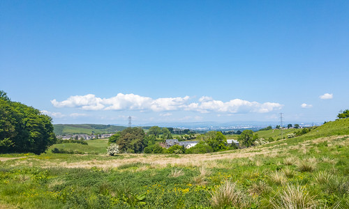 A landscape photo showing a view out over farmland and on the a cityscape in the distance.