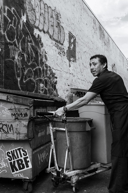 man emptying trash in alley
