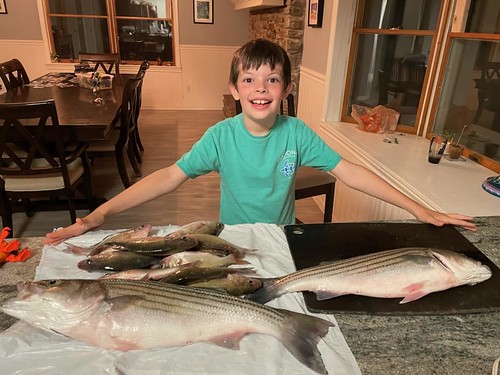 Photo of boy in a house with several fish on a table