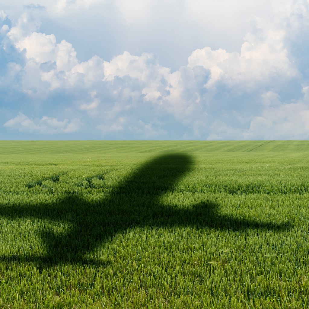 A photo of the shadow cast by an airliner on a green field