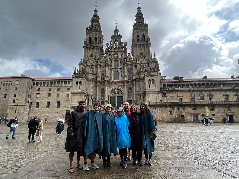 The group in ponchos standing in front of an ancient church building