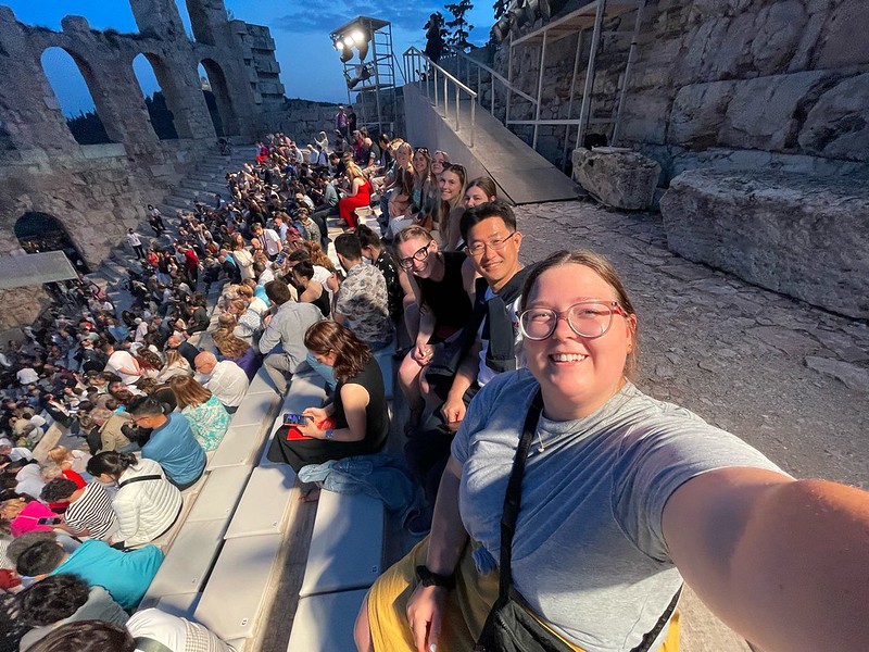 Selfie of the group sitting outside in the stands of a Greek opera house 