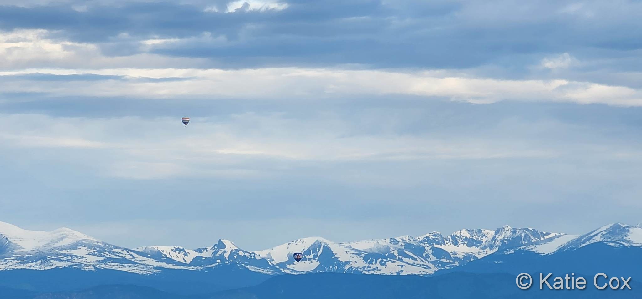 Hot air balloons take flight in front of the Rocky Mountains. (Katie Cox)