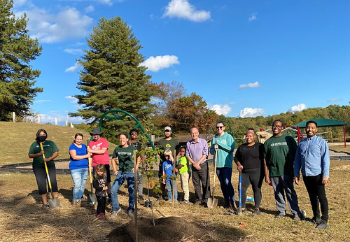 Photo of group of a dozen people posing with newly planted trees