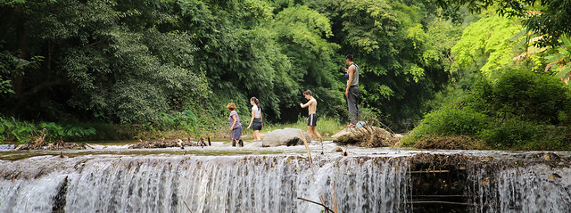 Crossing the river on foot at Tat Luang cascade waterfall
