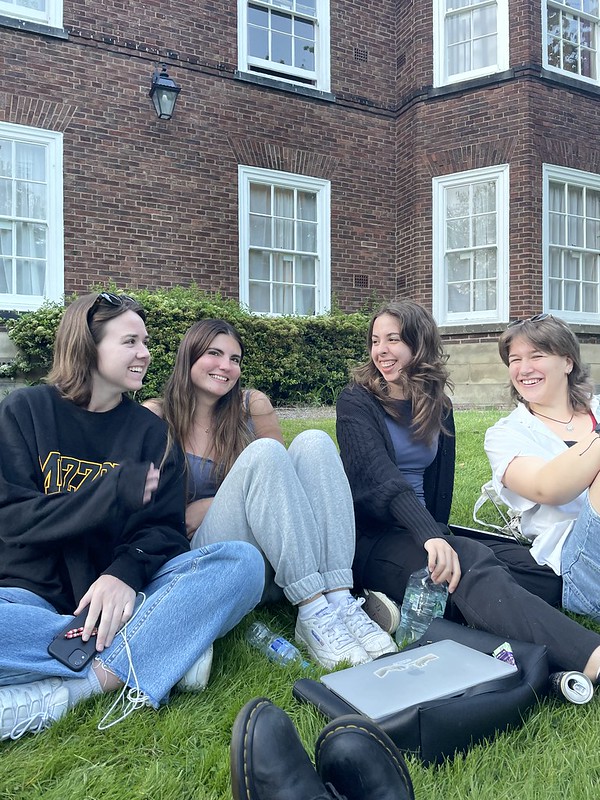 Group sitting out on the grass lawn outside of their dorm