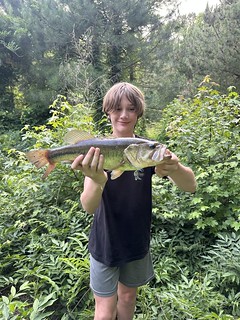 Photo of boy in a wooded area holding fish