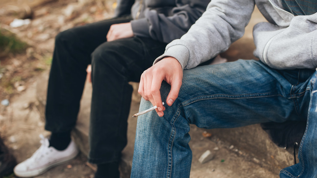 Two young people sat on a step smoking cannabis.