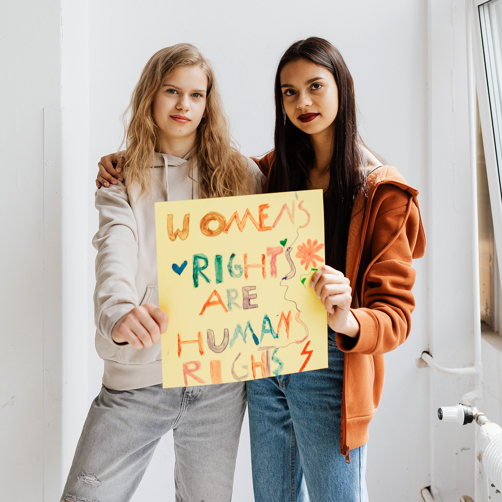 Two young women holding a handwritten sign that says 'women's rights are human rights'.