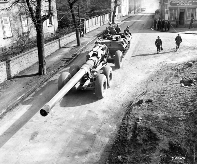 SC 201671 - With the gun crew riding on top, a tank destroyer chassis tows a huge Seventh Army 8-inch rifle through a French town, on the way to the front. 26 February, 1945.