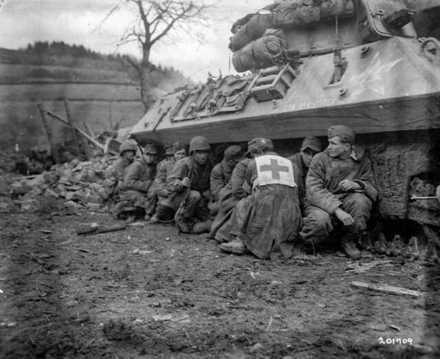 SC 201709 - German prisoners and their American guard crouch behind an American tank destroyer for protection against a barrage of German SP guns and 