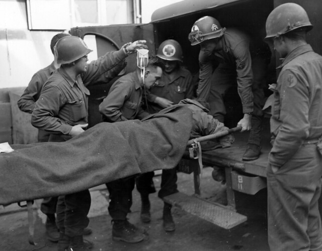 SC 201691 -  Medics carry a wounded infantryman into aid station of 103rd Division of 7th U.S. Army near Obermodern, France. Man was wounded by anti-personnel mine while on patrol. 27 February, 1945.