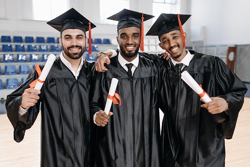 Three men in Black graduation attire smile and hold up their diplomas - Top 5 Reasons To Graduate High School