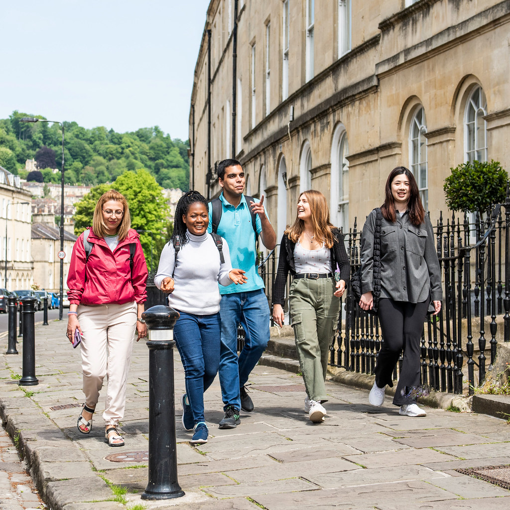 A group of students walking past Georgian buildings in Bath city centre.