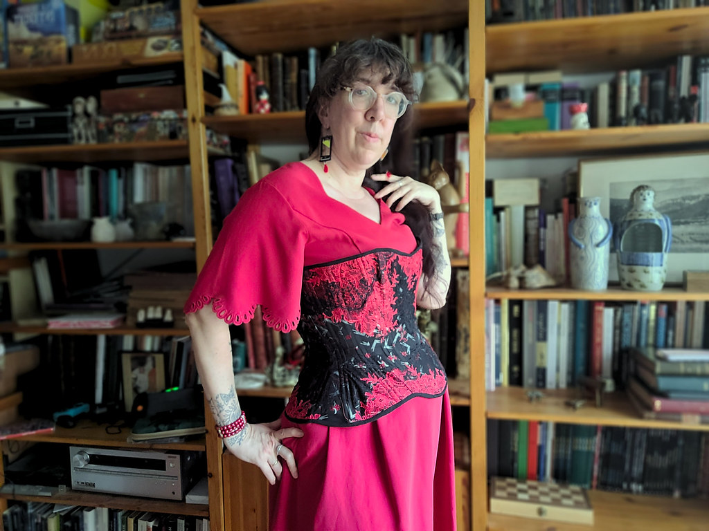 Femme de trois-quart face, portant un corset noir avec dentelle rouge