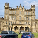West Virginia Penitentiary, Moundsville, WV Built in 1866-1876, this Gothic Revival-style prison was based on the Joliet Prison in Illinois, and was constructed using prison labor. The building features a limestone exterior with crenellated parapets, cylindrical and octagonal towers, rough-hewn stone on the wings and smooth-faced stone on the front facade of the central wing, double-hung windows, a central four-story administrative wing with a gable parapet, porch with gothic arches and decorative columns, buttresses on the exterior facades of the prison wings, and large walled yards to the rear of the building.   The prison operated until 1995, when it closed, and inmates were transferred to more modern facilities elsewhere in the state.  The building was listed on the National Register of Historic Places in 1996, and today serves as a prison guard training facility, tourist attraction with tours and haunted house events, a museum, and a filming location.