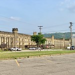 West Virginia Penitentiary, Moundsville, WV Built in 1866-1876, this Gothic Revival-style prison was based on the Joliet Prison in Illinois, and was constructed using prison labor. The building features a limestone exterior with crenellated parapets, cylindrical and octagonal towers, rough-hewn stone on the wings and smooth-faced stone on the front facade of the central wing, double-hung windows, a central four-story administrative wing with a gable parapet, porch with gothic arches and decorative columns, buttresses on the exterior facades of the prison wings, and large walled yards to the rear of the building.   The prison operated until 1995, when it closed, and inmates were transferred to more modern facilities elsewhere in the state.  The building was listed on the National Register of Historic Places in 1996, and today serves as a prison guard training facility, tourist attraction with tours and haunted house events, a museum, and a filming location.
