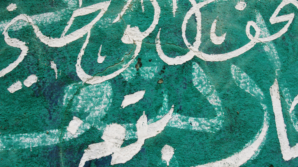 Arabic graffiti painted on a green wall.