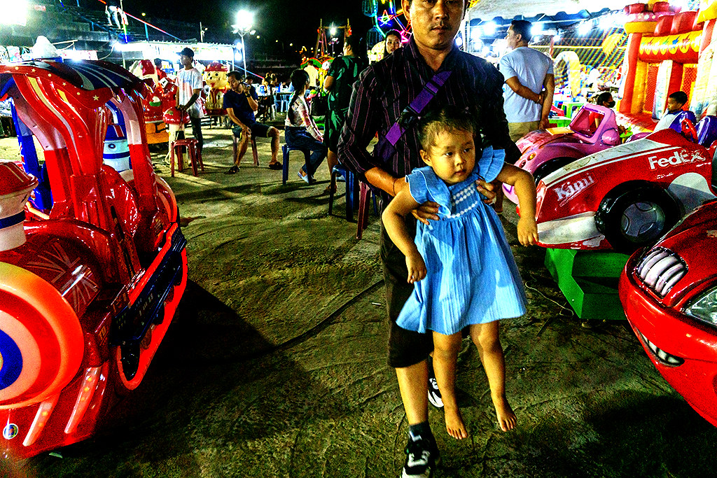 Man holding girl by armpits at night market on 7-20-23--Vientiane copy