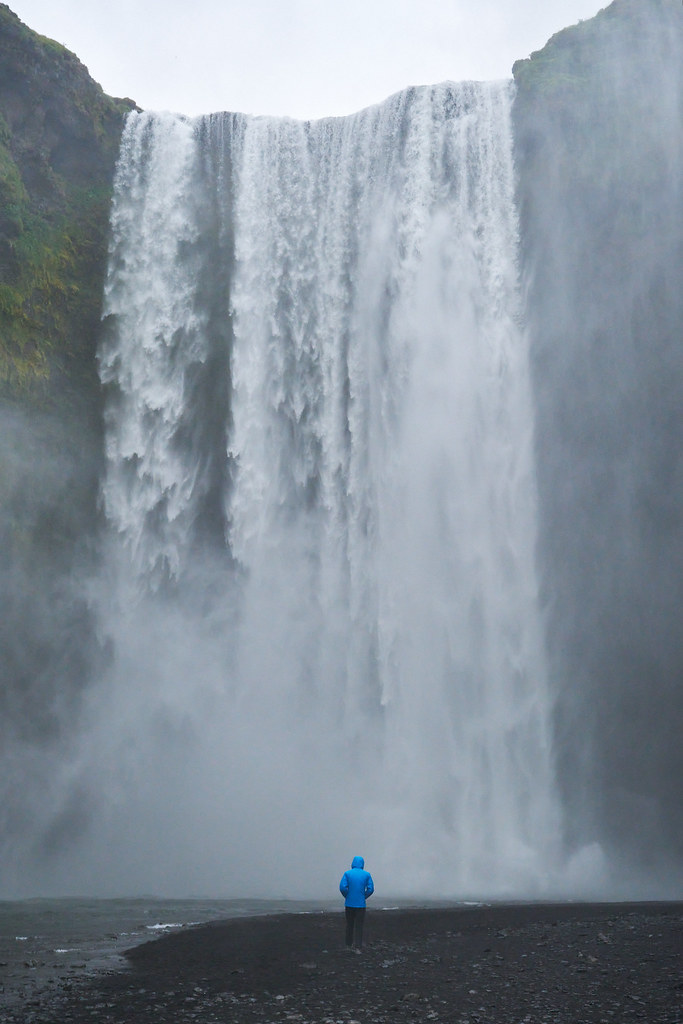 person standing in front of massive waterfall