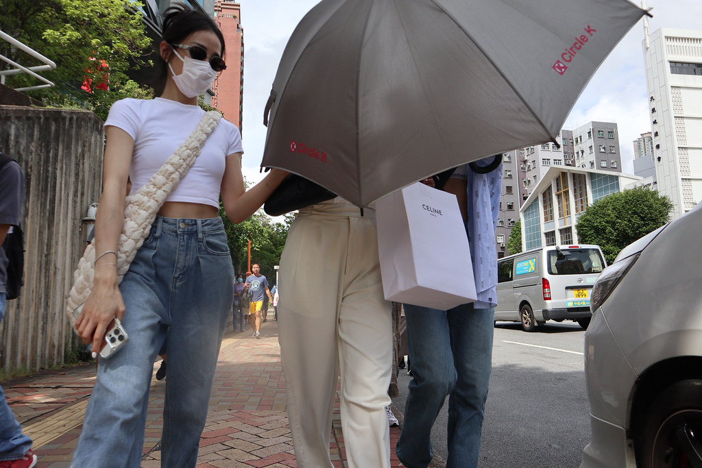 被告潘巧賢（中間）在兩名友人陪同下離開法院，並以雨傘遮擋鏡頭