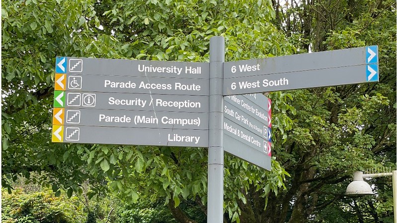 A signpost on the University campus. Various buildings and locations are indicated in different directions.
