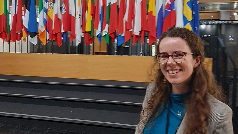 A woman standing in front of a selection of European country flags