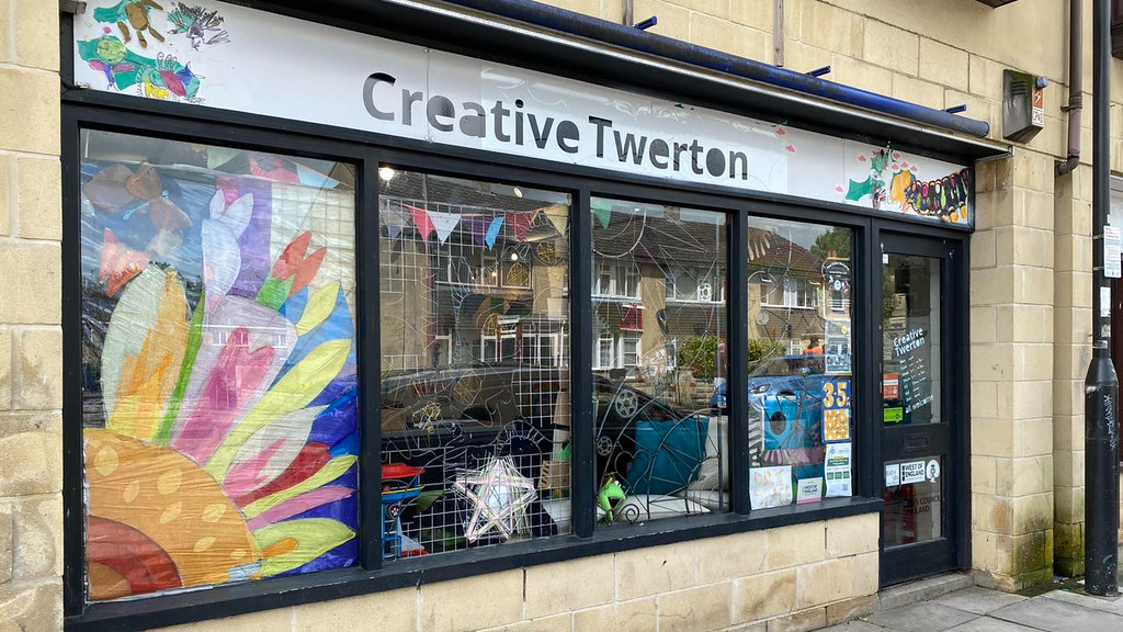 Shop front with window filled with art work with a sign over the entrance that says Creative Twerton