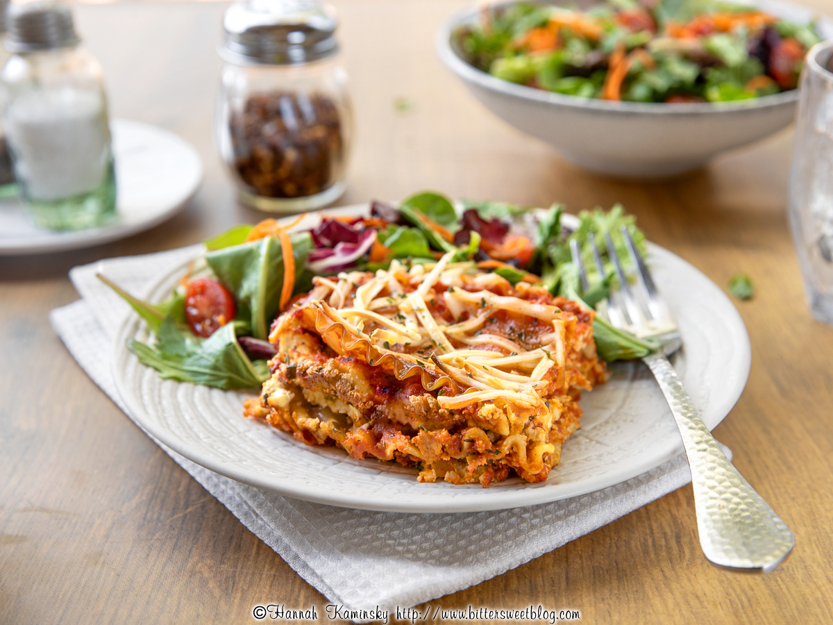 A slice of lasagna on a plate with salad.