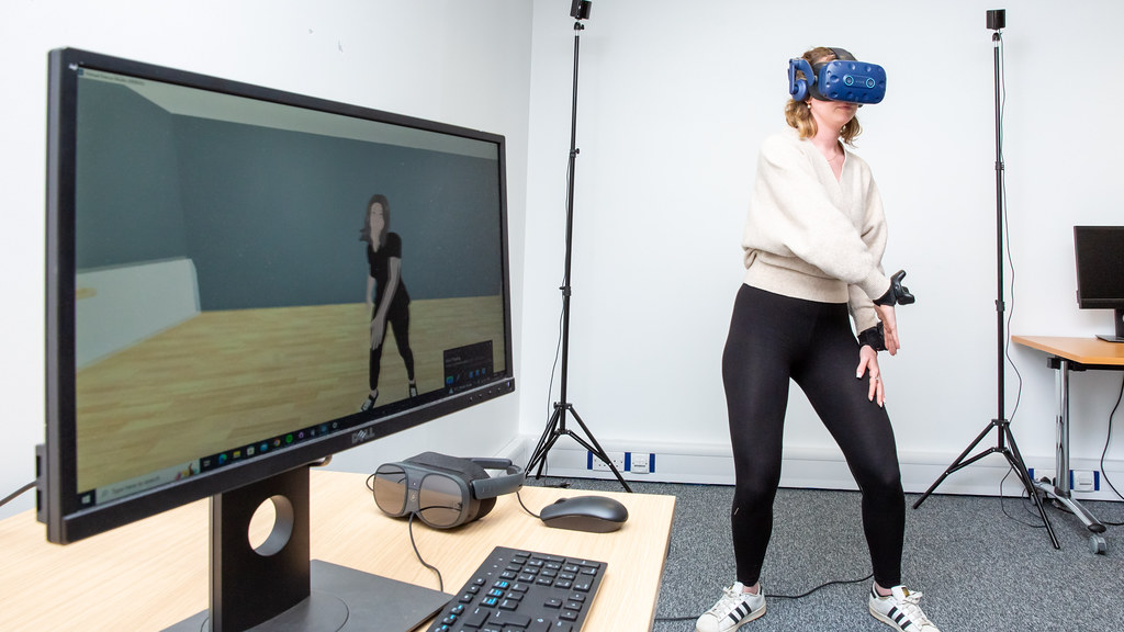 Woman wearing VR headset learning dance moves in front of computer