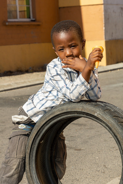Boy with an Ice Cream Cone Resting on a Tyre in Longa Township in Cape Town - South Africa 96