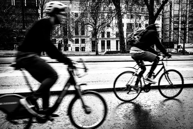 Two men cycling through kensington on their bikes.