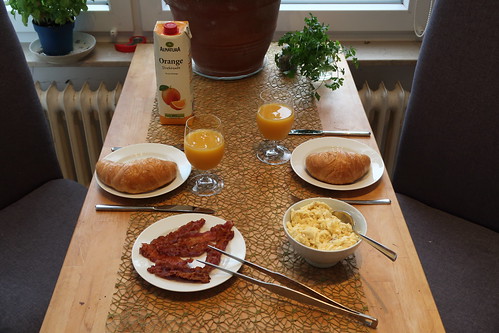 Orangensaft zu Rührei mit Bacon und Croissants (Tischbild)