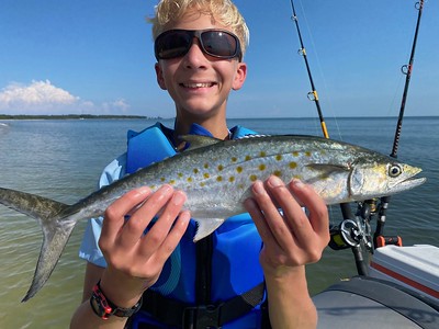 Photo of boy holding a fish on a boat