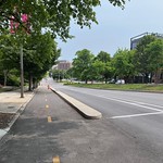 Protected bike lane (view facing southeast) on Mount Royal Avenue, Baltimore, MD 21217 Photograph by Eli Pousson, 2023 May 23.