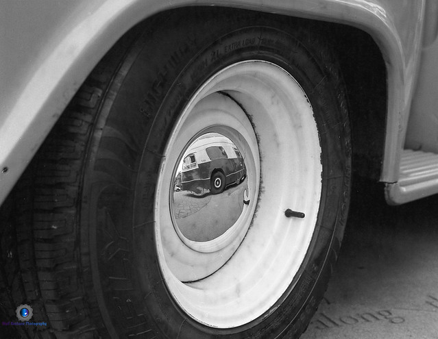 1969 West Midlands Daimler Fleetline bus, reflected in the hubcap of a Chevrolet pick-up.