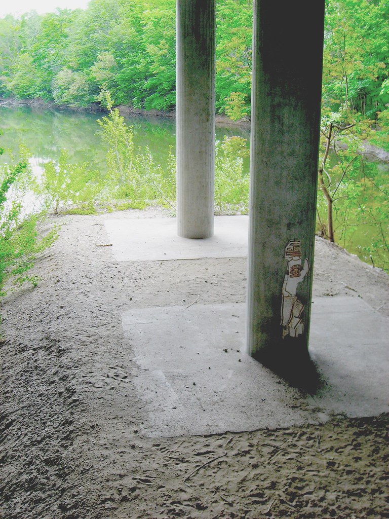 concrete pillars Urban nature and a tiny piece of street-art underneath the road in praterpark Wien or Vienna with still sirup-like water