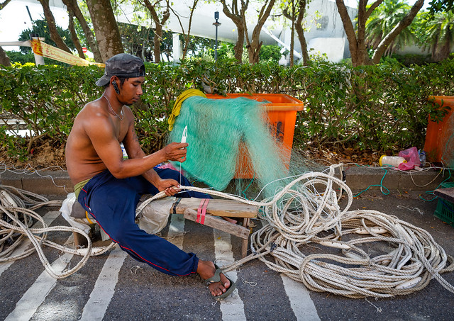Indonesian man repairing a fishing net at Tamsui Fisherman Wharf, New Taipei, Tamsui, Taiwan