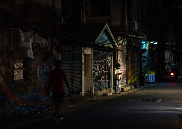 Taiwanese woman looking at her mobile phone in a street at night, Taipei, Taipei, Taiwan