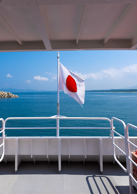 Japanese flag on a ferry  in front of the sea, Kyushu region, Fukuoka, Japan