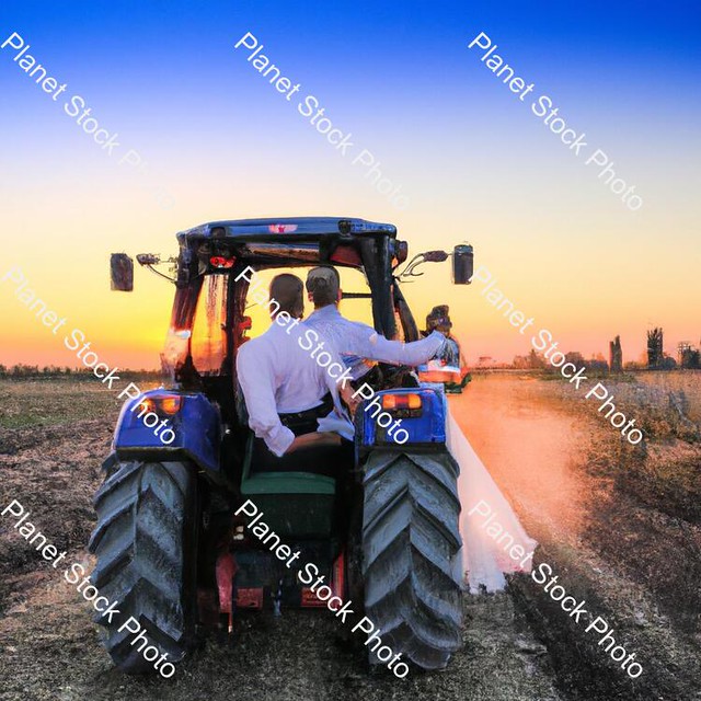 A Newly Married Couple Driving a Tractor Through the Grain Field Towards the Horizon at Sunset  - Stock photo with image ID: 7bafa140-18bf-4a04-aa99-221a91942fe5