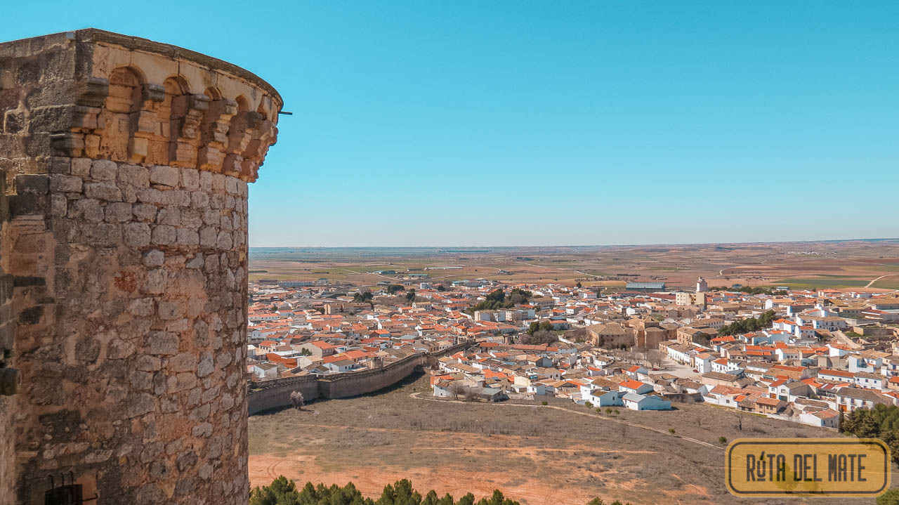 Vistas desde la muralla del Castillo de Belmonte. A la izquierda, una de sus torres de defensa. Se puede observar cómo la muralla de Eugenia de Montijo desciende hasta el pueblo que se encuentra rodeado de un paisaje manchego.