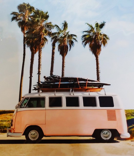 Classic Volkswagen Micro Bus at the Southern California Beach with surf boards and palm trees on the side. Picture of a graphic in an antique store