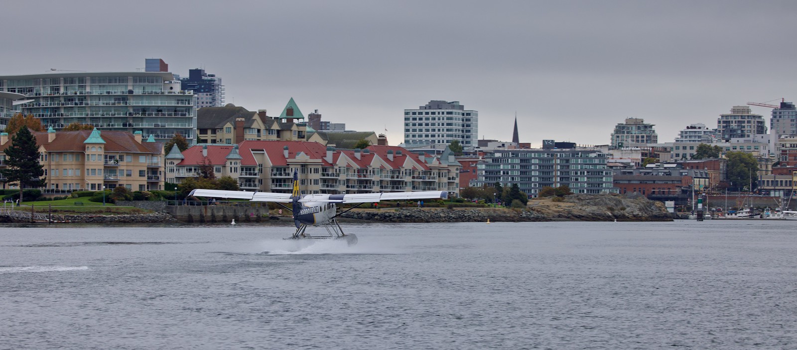 Harbour Air seaplane landing in the harbour with Songhees condos and the downtown